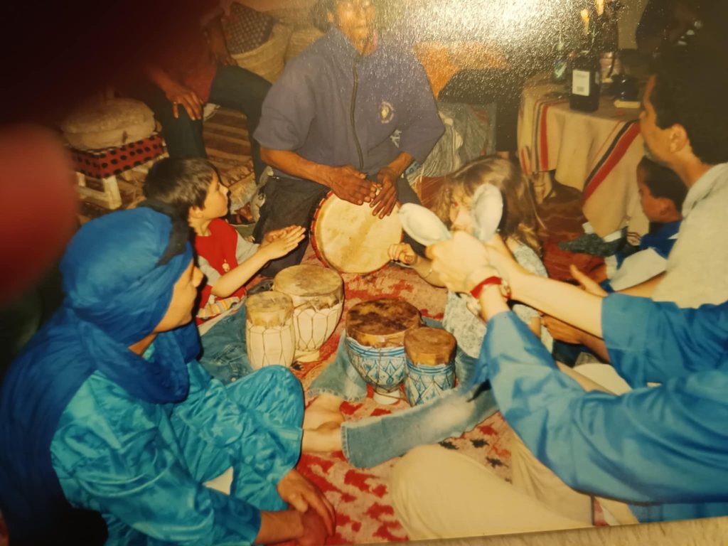 A group sitting on the floor playing traditional drums together indoors in Morocco